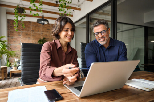 Business team two executives working together using laptop computer in office.