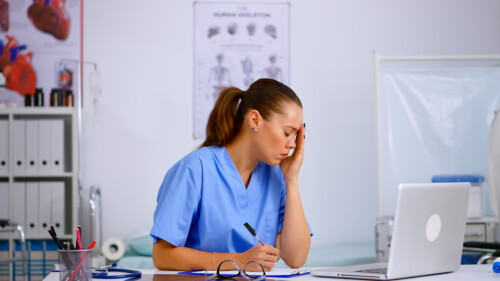 Tired healthcare medical assistant working in hospital researching