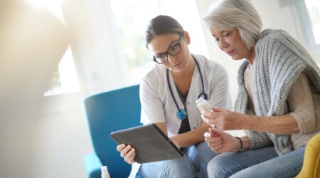 Doctor going through results and medication on tablet with seni