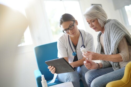 Doctor going through results and medication on tablet with seni