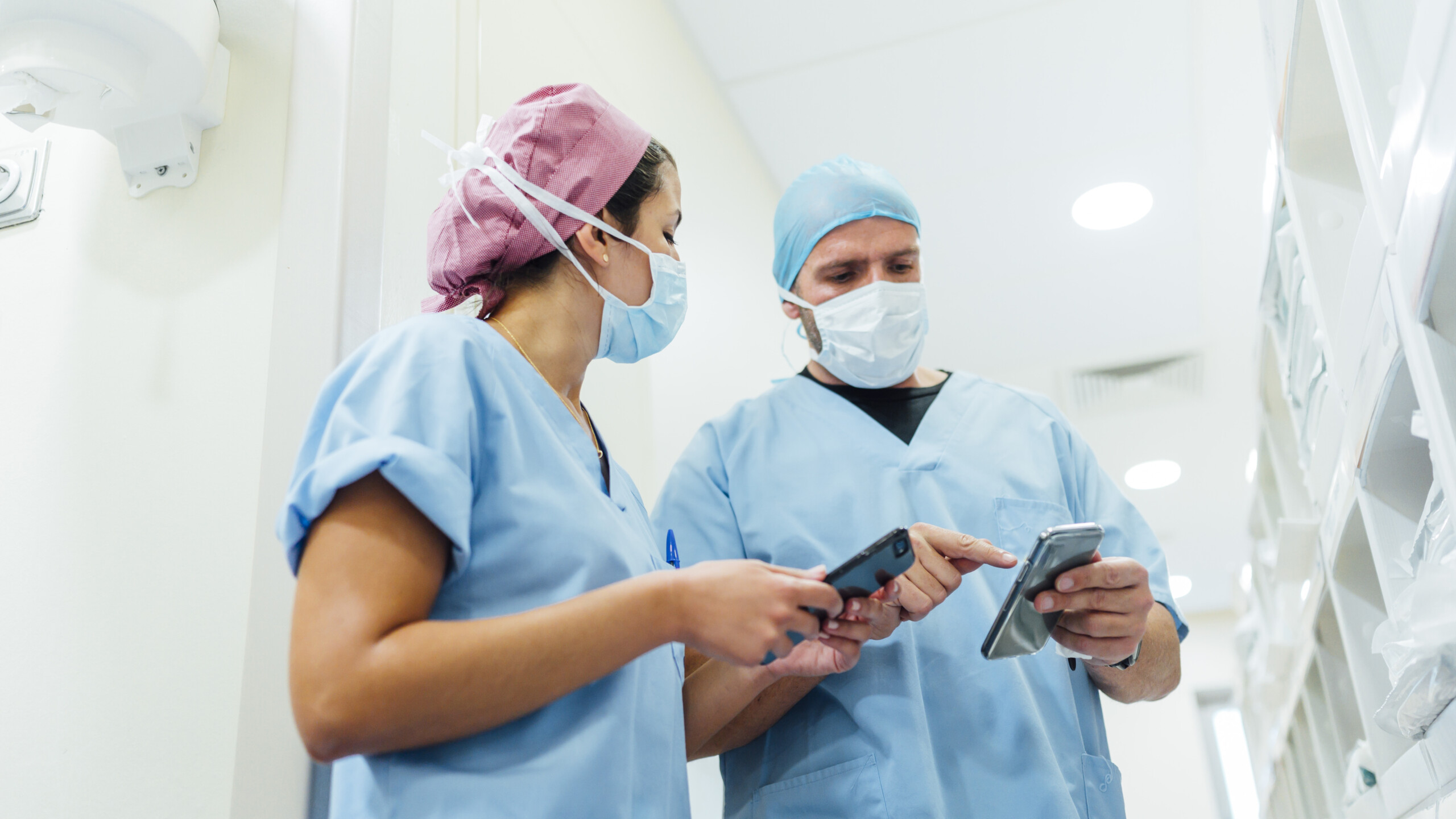 Doctors using cell phones in the hospital corridor. Medical concept